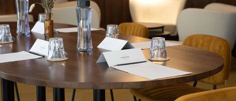 A conference table with name cards, glassware, and a vase with dried flowers.