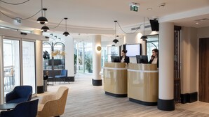 A modern hotel lobby with a reception desk, seating area, and large windows. - Mercure Lyon Centre Charpennes Parc de la Tete d'Or (Villeurbanne)