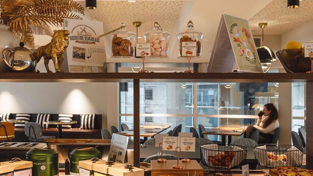 A café with a variety of baked goods, pastries, and a seating area with tables and chairs. - Mercure Lyon Centre Charpennes Parc de la Tete d'Or (Villeurbanne)