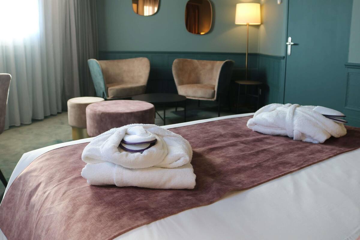A hotel room with a bed, two armchairs, a small round table, and a lamp.