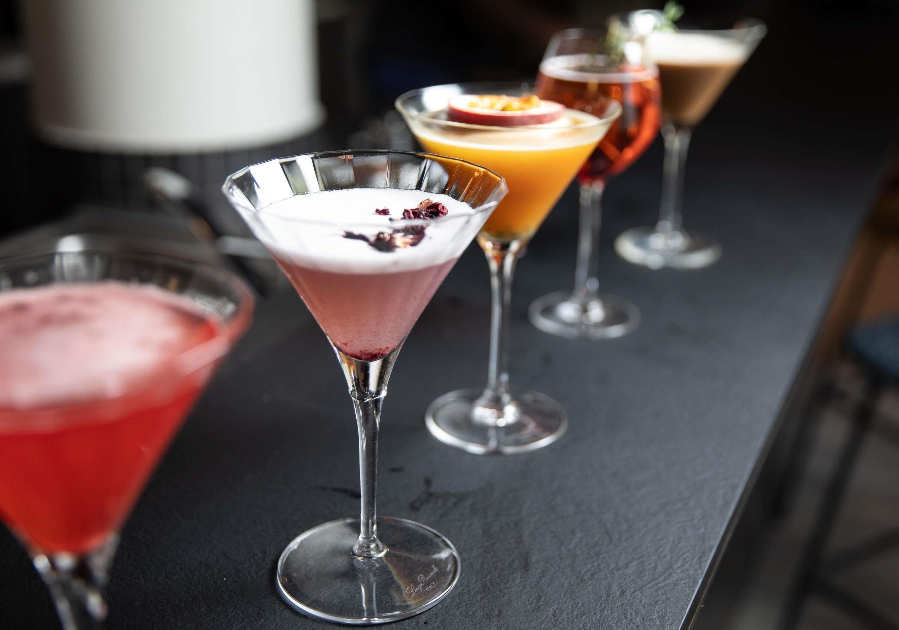 A bar with various cocktails in martini glasses.