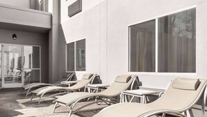 A poolside area with lounge chairs and a stone floor.