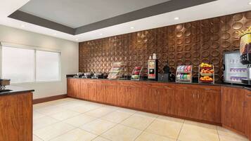 A modern kitchen with wooden cabinets, a coffee station, and a fruit display.