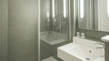 Een moderne badkamer met een douche met glazen wand, een wit wastafelmeubel en een spiegel.