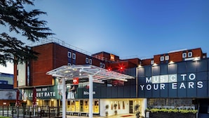 Un edificio moderno con un letrero que dice 'MUSIC TO YOUR EARS' y una entrada con un porche cubierto.