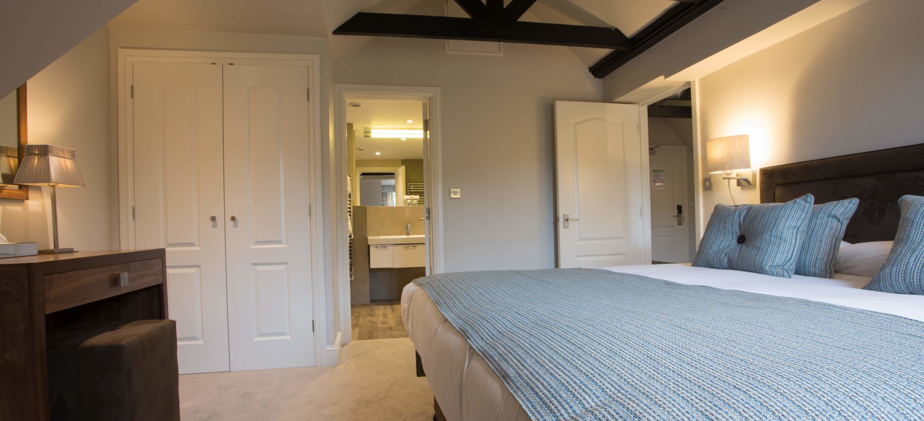 A bedroom with a large bed, a bedside table, a lamp, and a wardrobe.