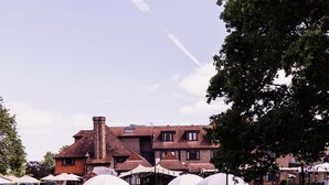 A courtyard with outdoor seating, a pond, and a building in the background. - Stirrups Hotel (Bracknell)
