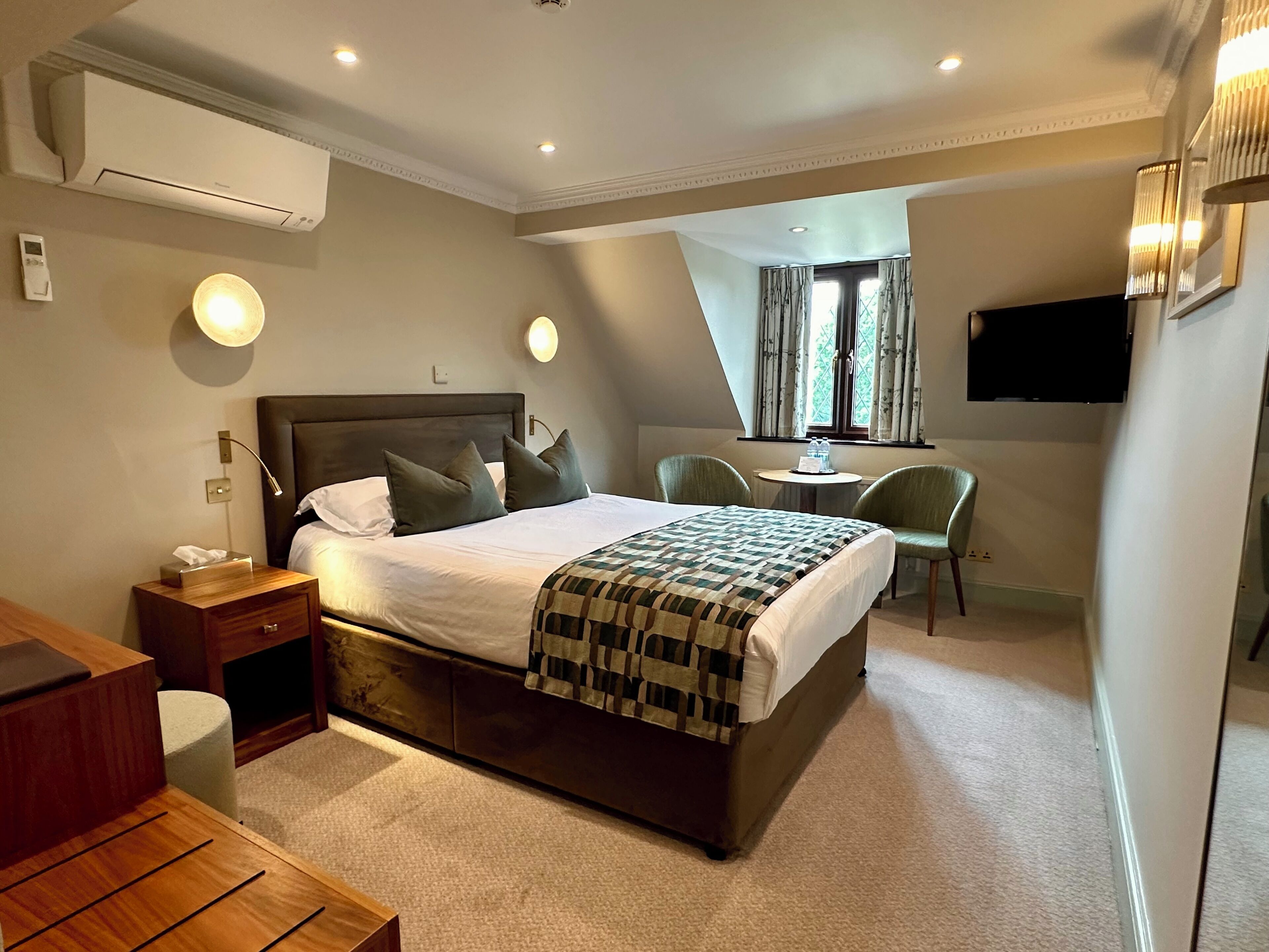 A hotel room with a large bed, bedside tables, a desk, and a chair.