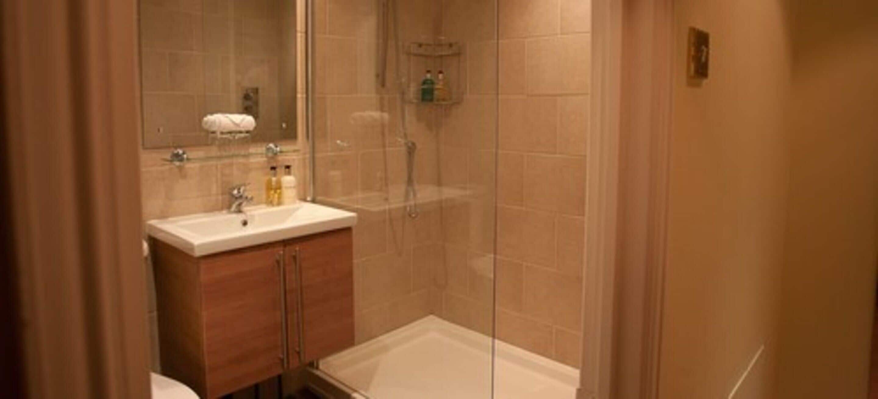 A bathroom with a glass-enclosed shower, a sink with a mirror, and a toilet.