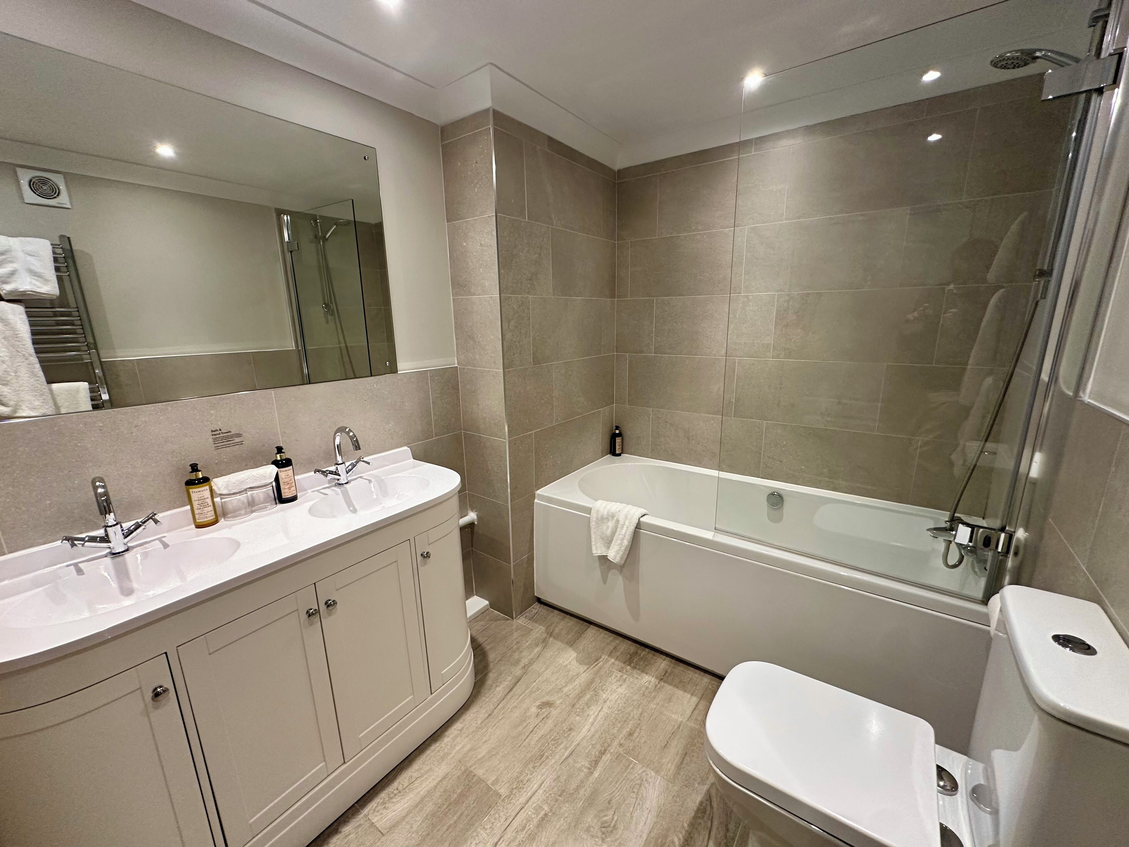 Une salle de bain moderne avec un meuble-lavabo à deux vasques, une baignoire et des toilettes.