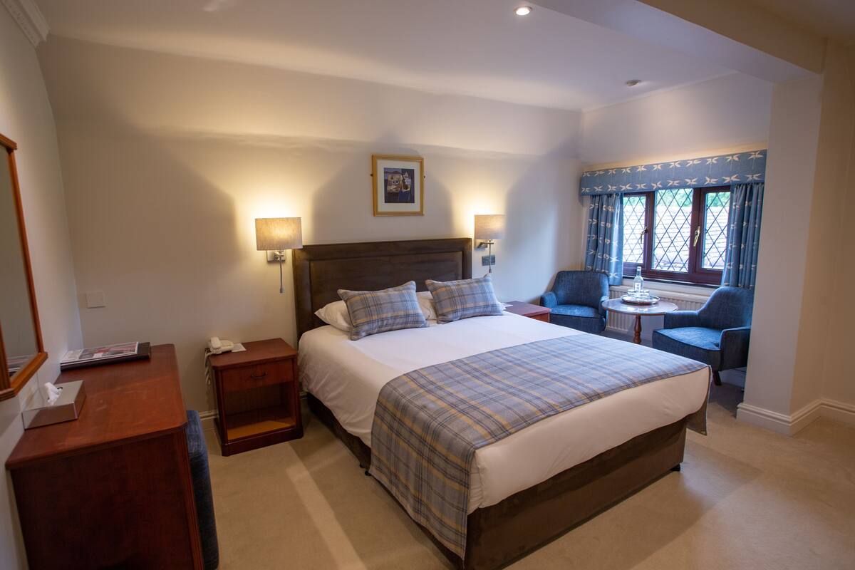 A bedroom with a large bed, bedside tables, a desk, and a chair.