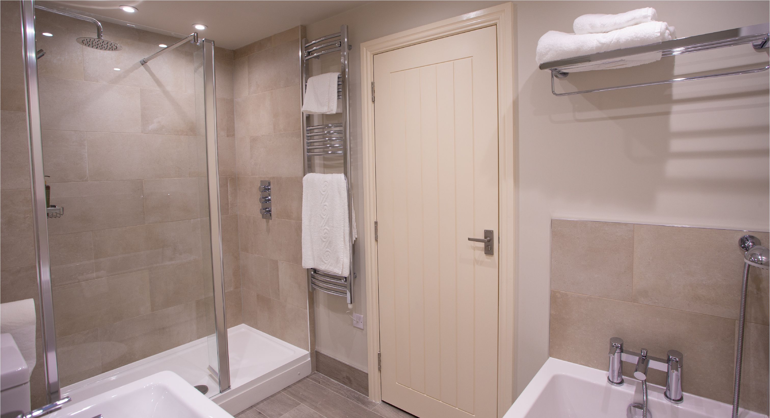 A modern bathroom with a glass-enclosed shower, a separate bathtub, and a walk-in shower stall.