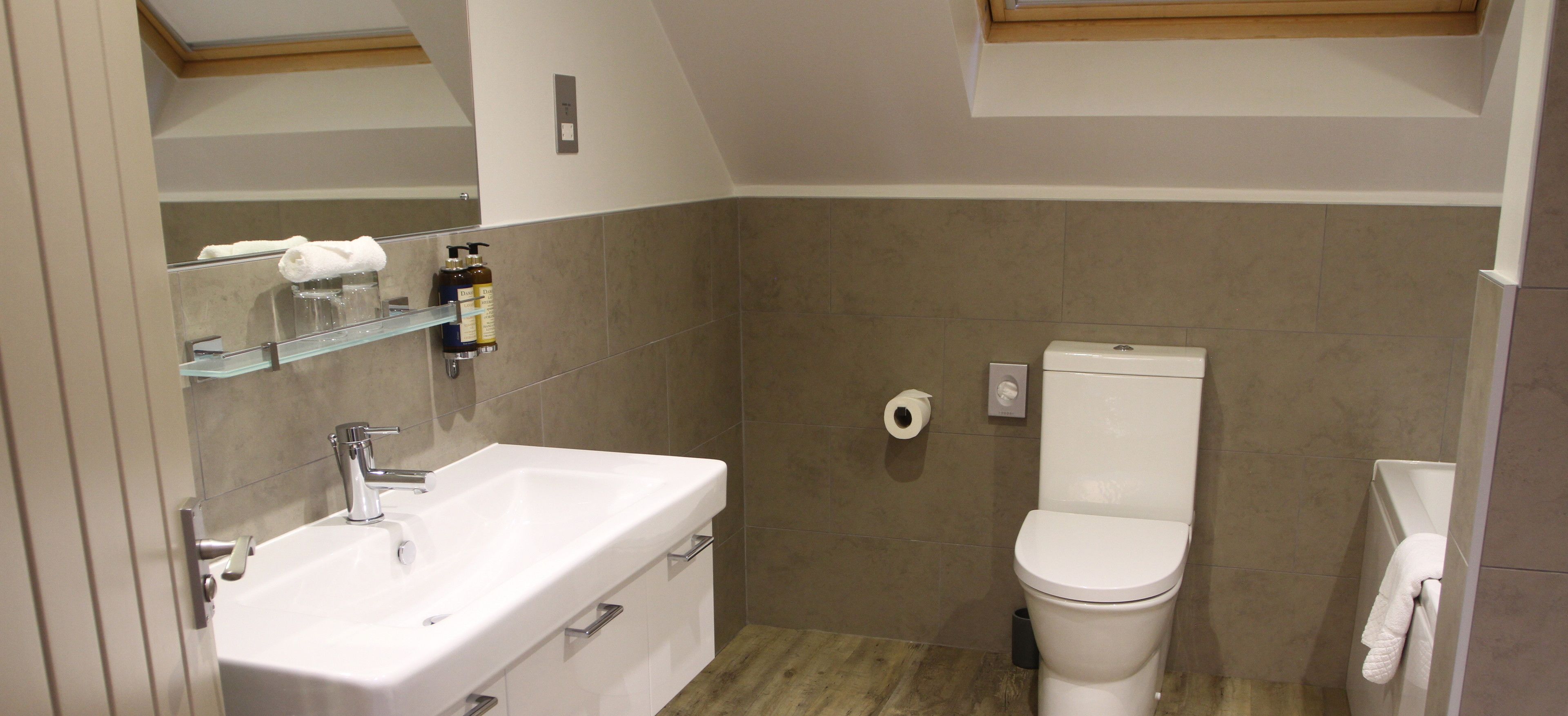 Une salle de bain avec un lavabo blanc, des toilettes et un miroir au-dessus du lavabo.
