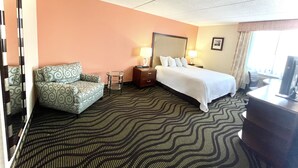 Una habitación de hotel con una cama, dos mesitas de noche con lámparas, un sofá, un escritorio y un televisor.