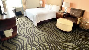 Habitación de hotel con una cama grande, un escritorio, una silla y una mesita.