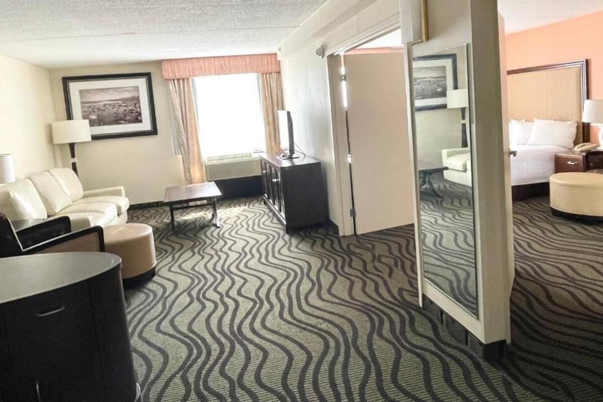 A hotel room with a sofa, a small table, a TV, and a bed.