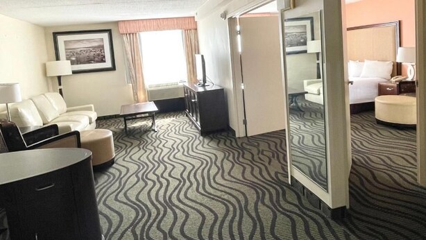 Una habitación de hotel con sofá, una mesita, televisor y cama.
