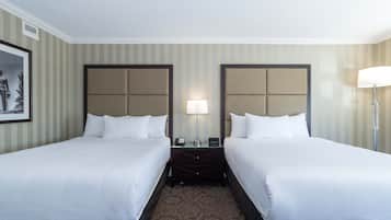 Une chambre d’hôtel avec deux lits, une table de chevet avec une lampe et un tableau encadré au mur.