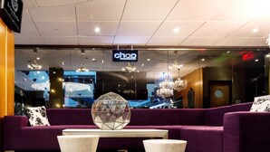 A modern lobby with a purple sofa, a glass wall, and a chandelier. - Sandman Signature Edmonton Downtown Hotel (Edmonton)