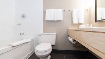 Kylpyhuone, jossa on valkoinen kylpyamme, wc ja peilillä varustettu pesuallas.