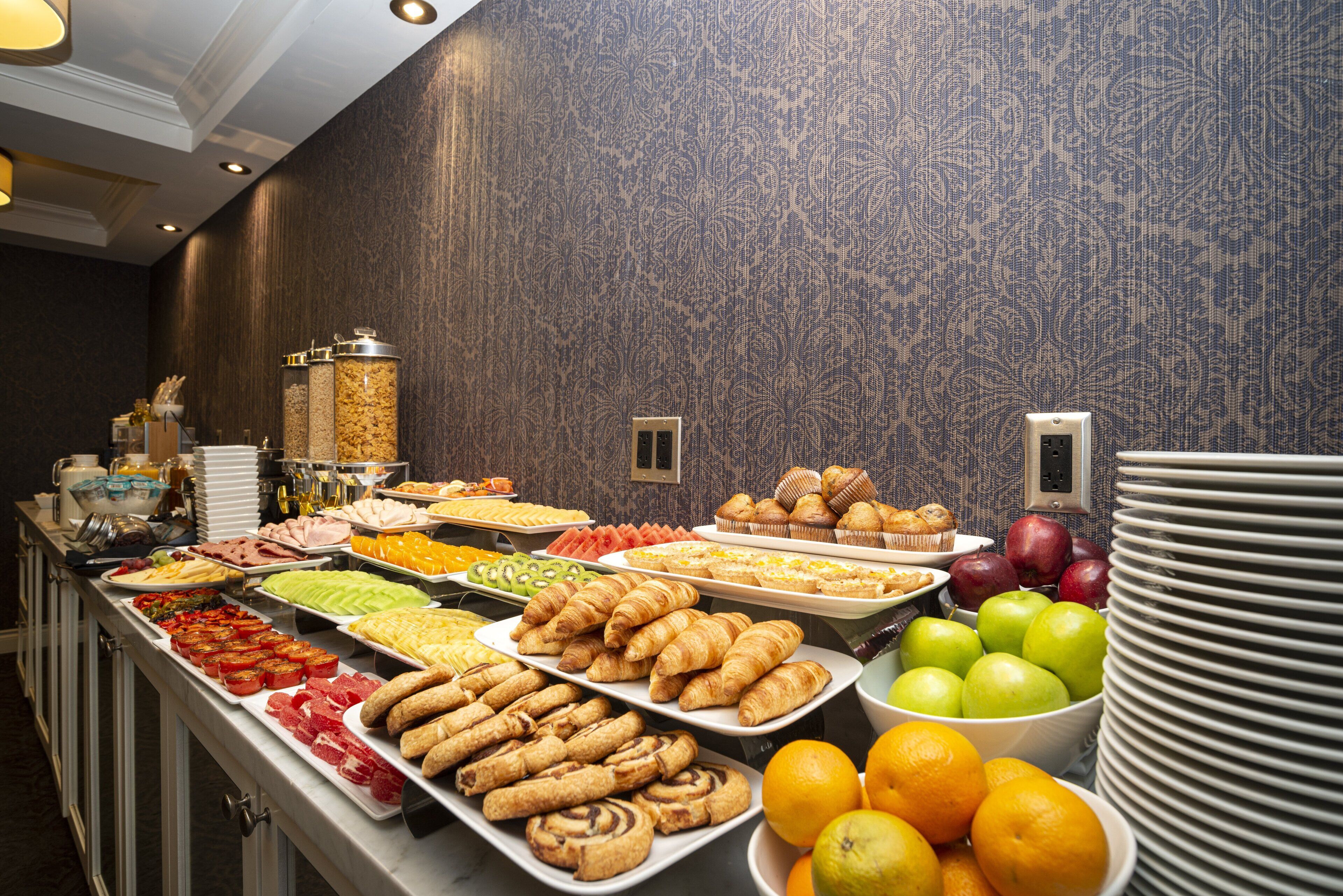 A buffet with various food items and a bowl of oranges.