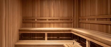 A wooden sauna with benches and a table, a glass, and a towel.