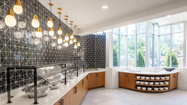 A modern kitchen with a geometric backsplash, a glass partition, and a built-in bowl rack.