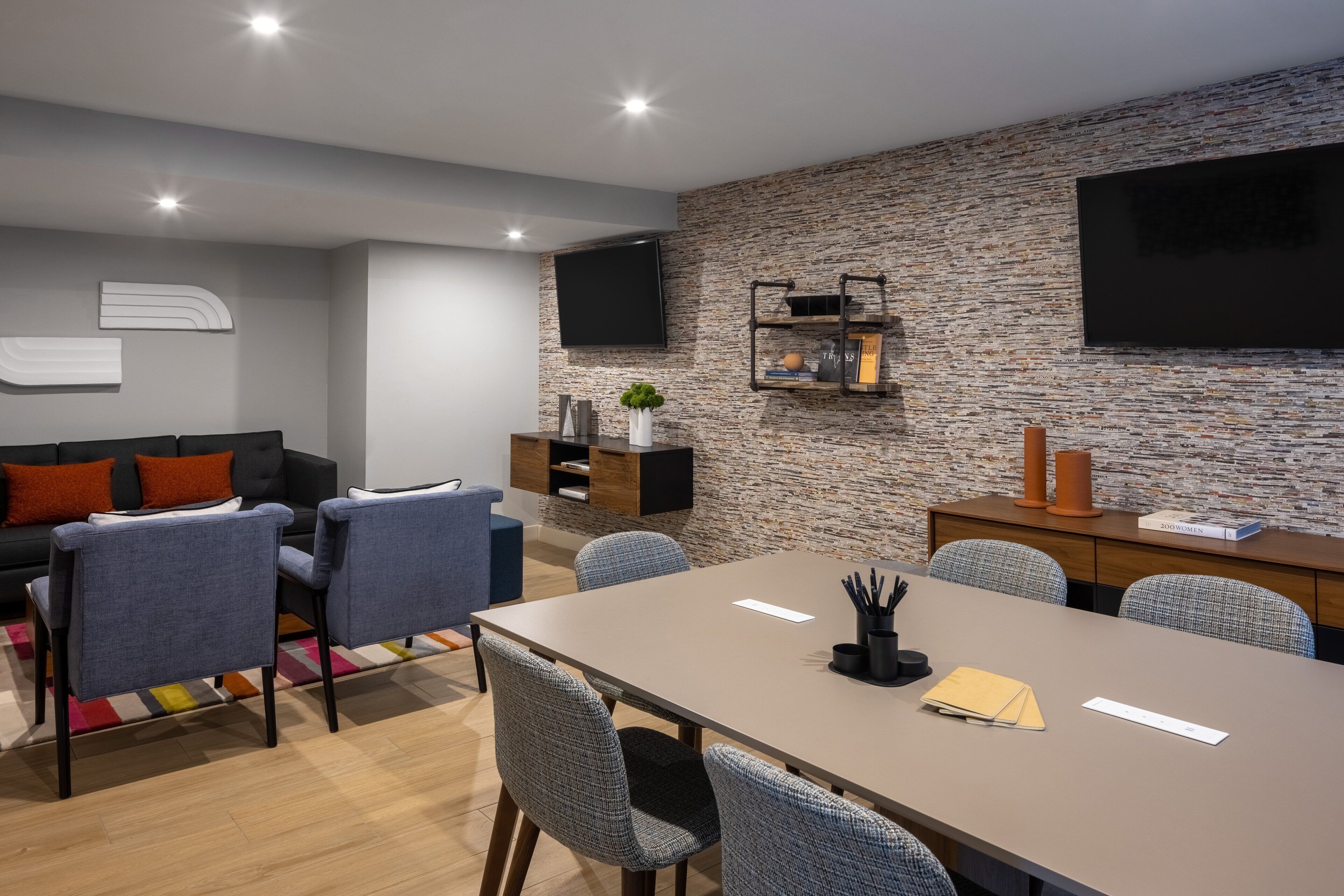 Una sala de estar moderna con un sofá, sillas, una mesa de centro y un televisor montado en una pared texturizada.