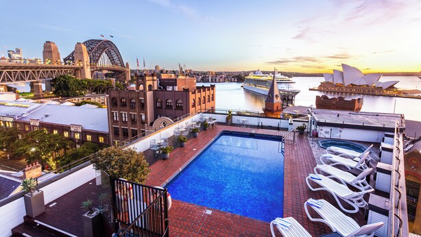 A rooftop pool with lounge chairs, a view of the Sydney Opera House, and the Sydney Harbour Bridge. - Sydney Harbour Hotel (The Rocks)