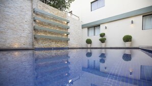 Un edificio moderno con piscina, escalones de piedra y plantas en macetas.