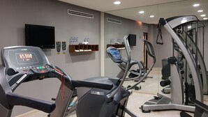 Un gimnasio con cintas de correr, elípticas y máquinas de pesas.