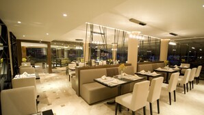 Un restaurante moderno con un diseño limpio y minimalista, que ofrece diversas opciones de asiento, incluyendo mesas y una zona con sofás.