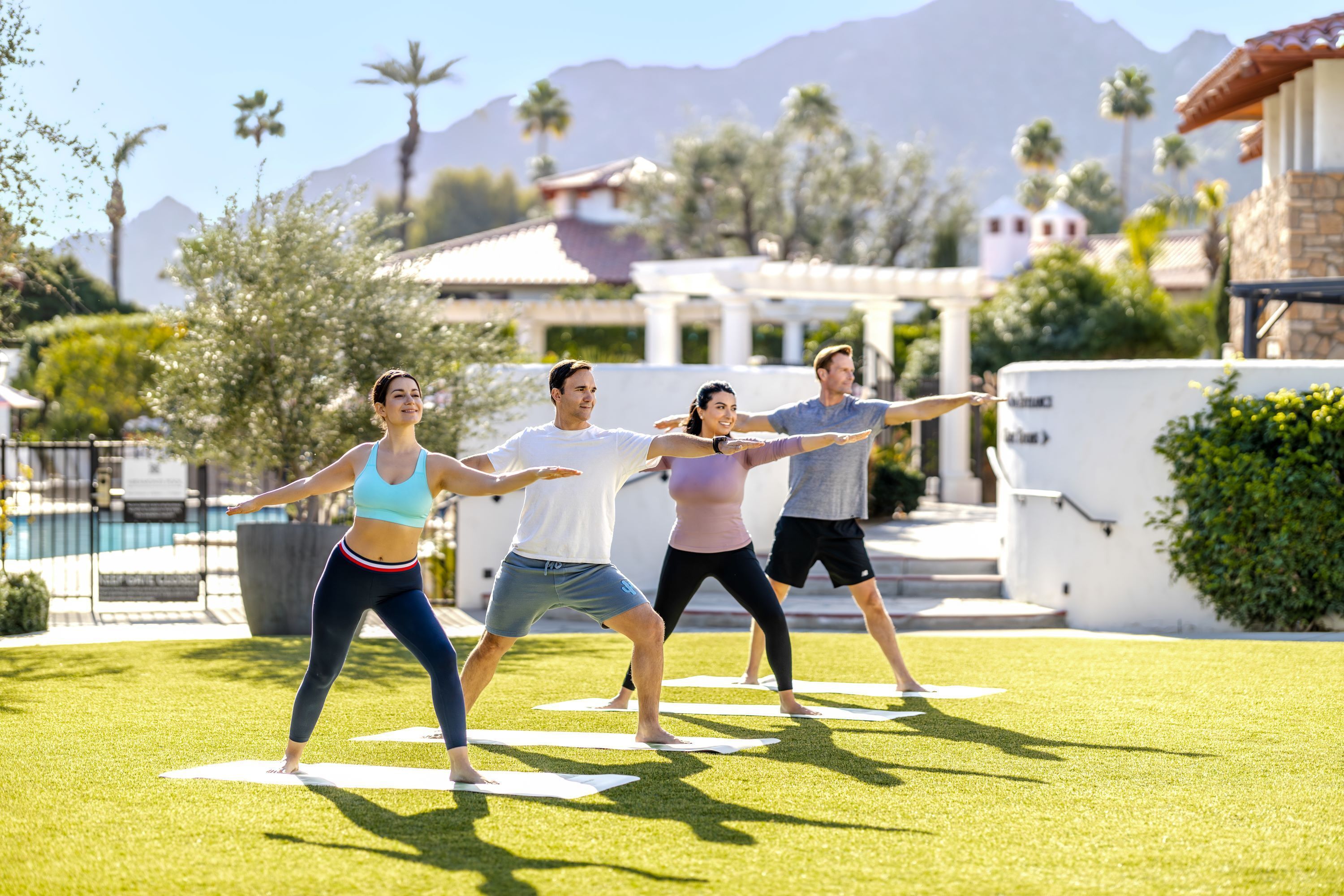 A group of people doing a yoga exercise outdoors on a sunny day.