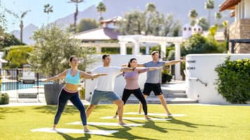 A group of people doing a yoga exercise outdoors on a sunny day.