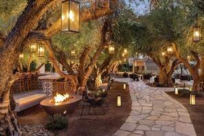 An outdoor seating area with stone pathways, fire pits, and hanging lanterns. - Tommy Bahama Miramonte Resort & Spa (Indian Wells)