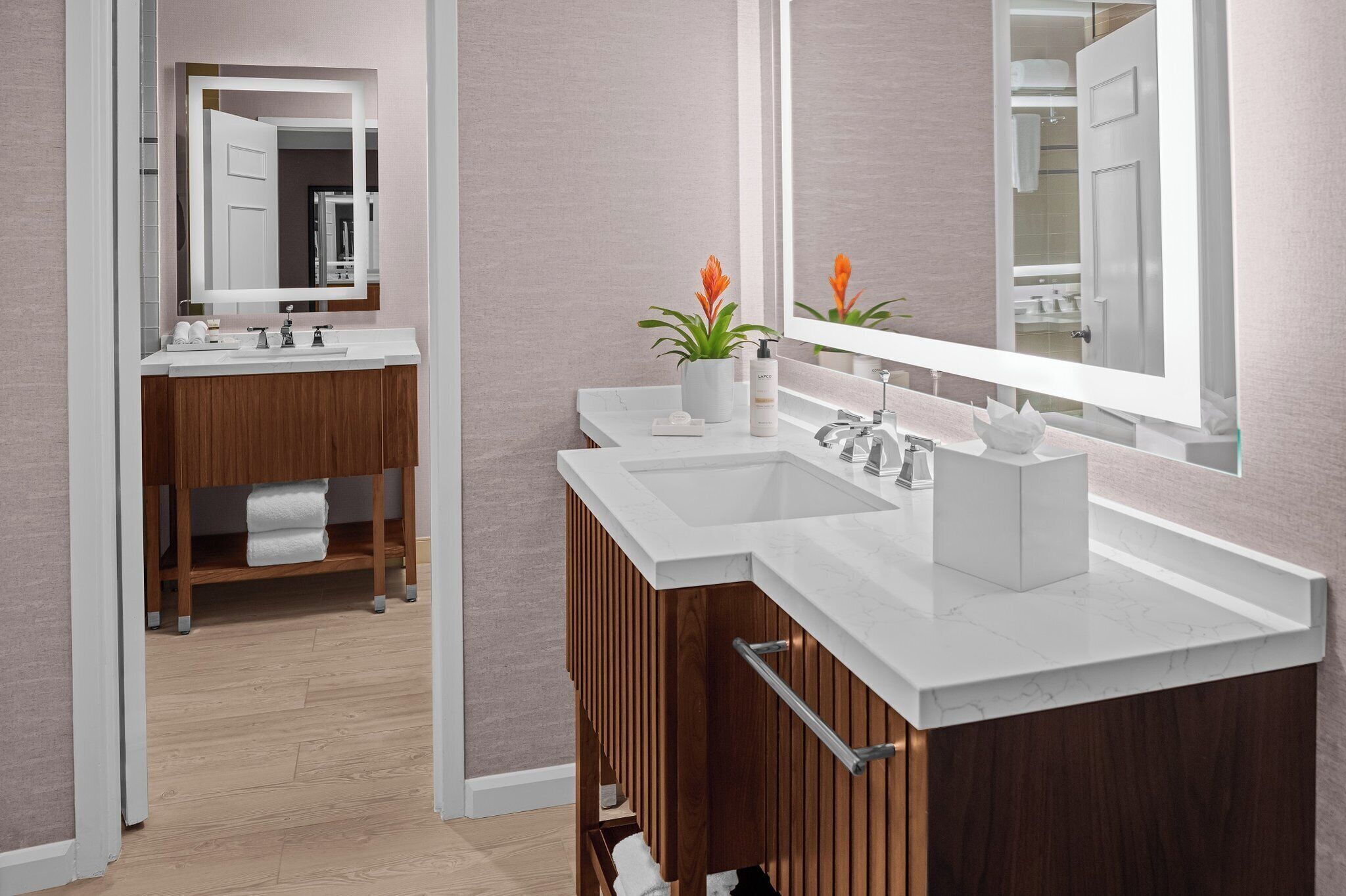Une salle de bain moderne avec un meuble-lavabo à deux vasques, des meubles en bois et un grand miroir.