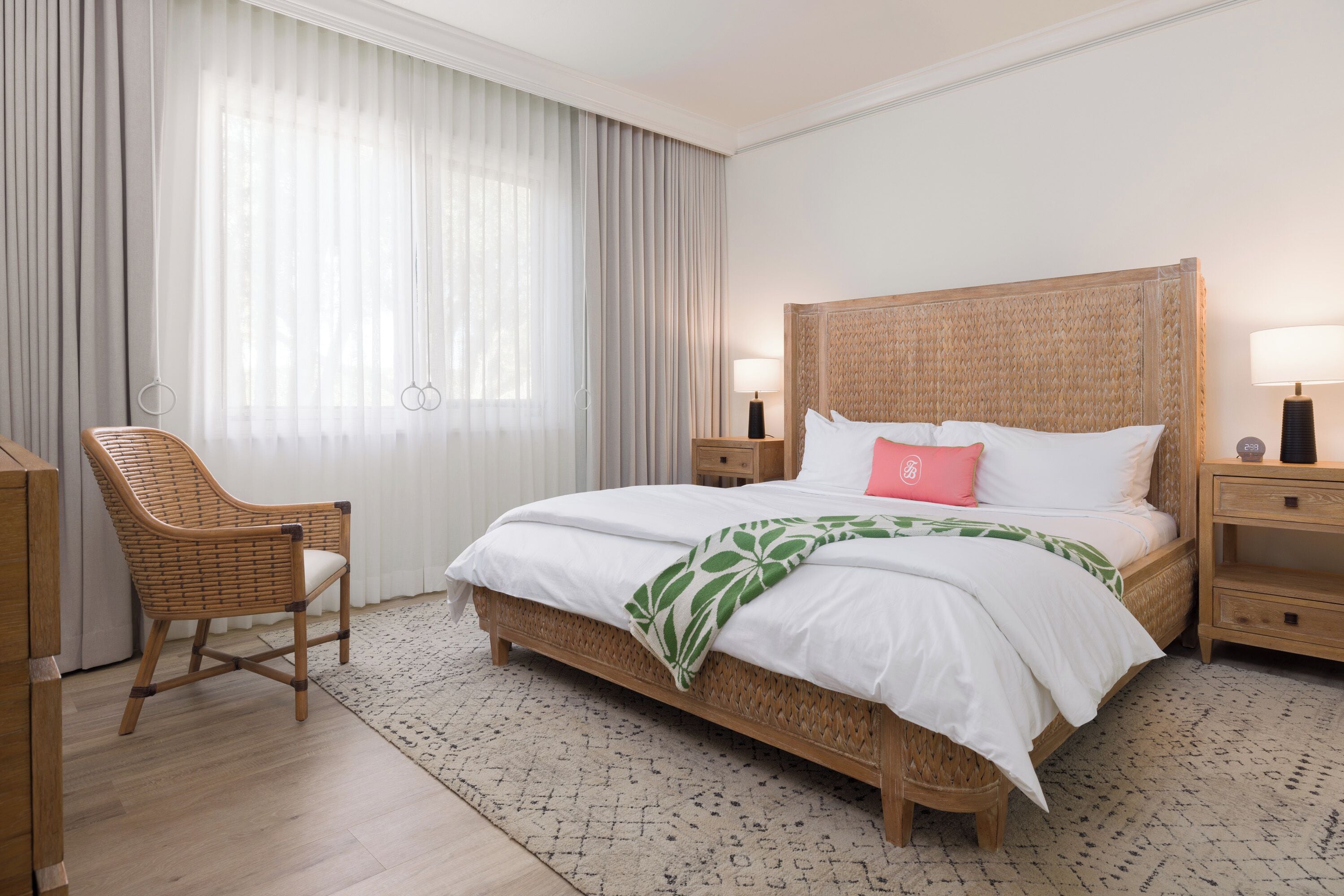 A neatly arranged hotel room with a large bed, a chair, and a bedside table with lamps.