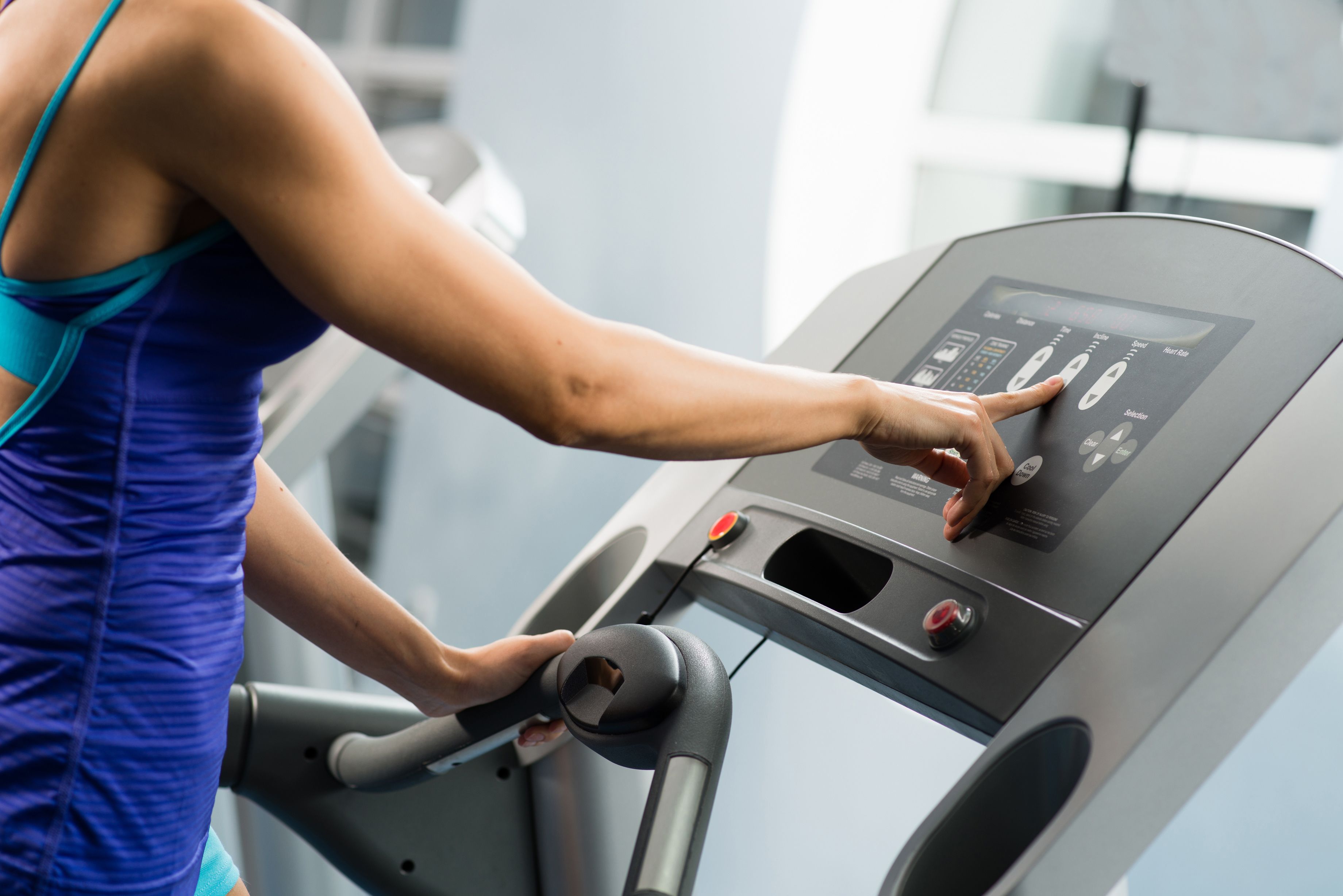 Eine Person trainiert auf einem Laufband mit digitaler Anzeige.