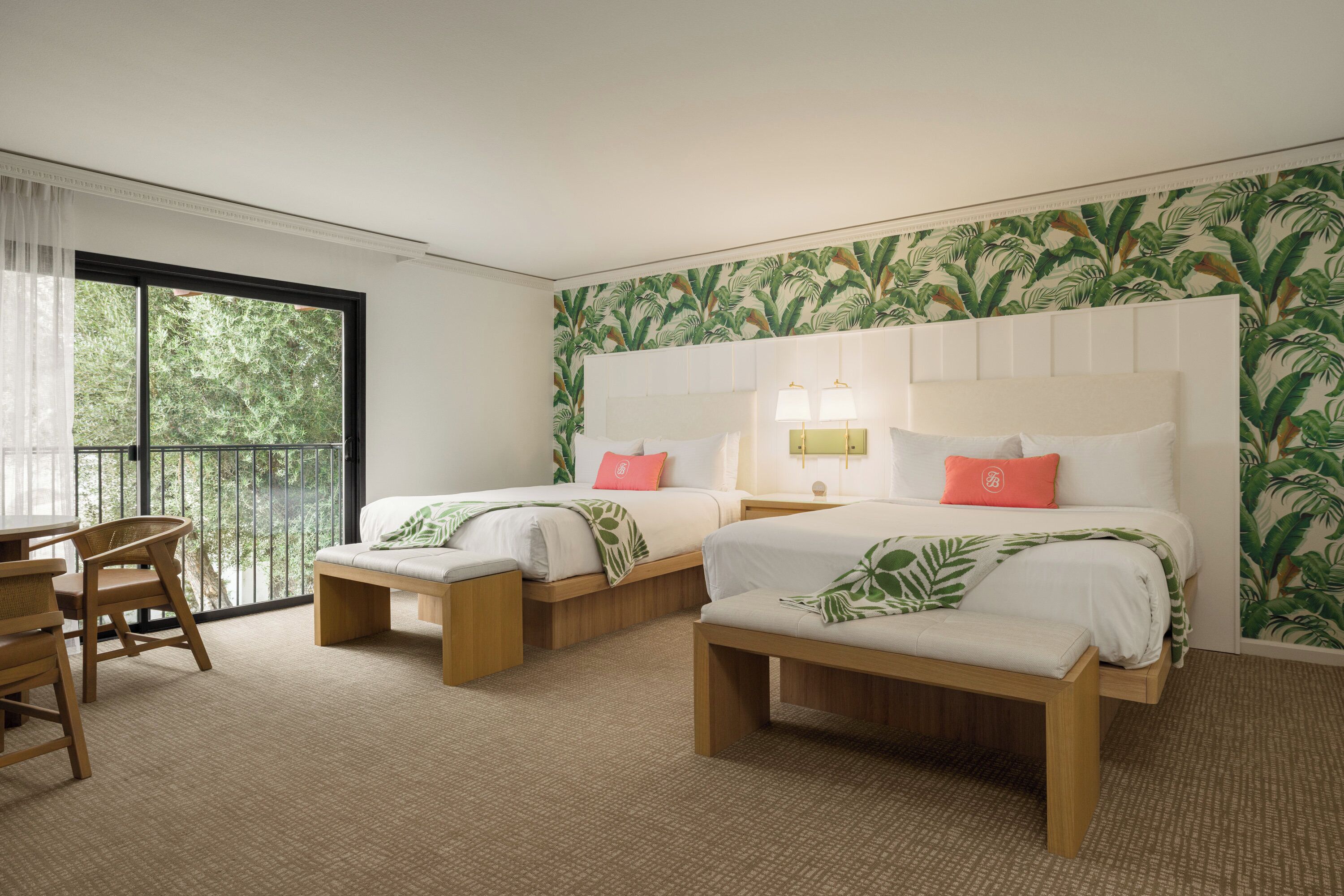A hotel room with two beds, a small table, and chairs.