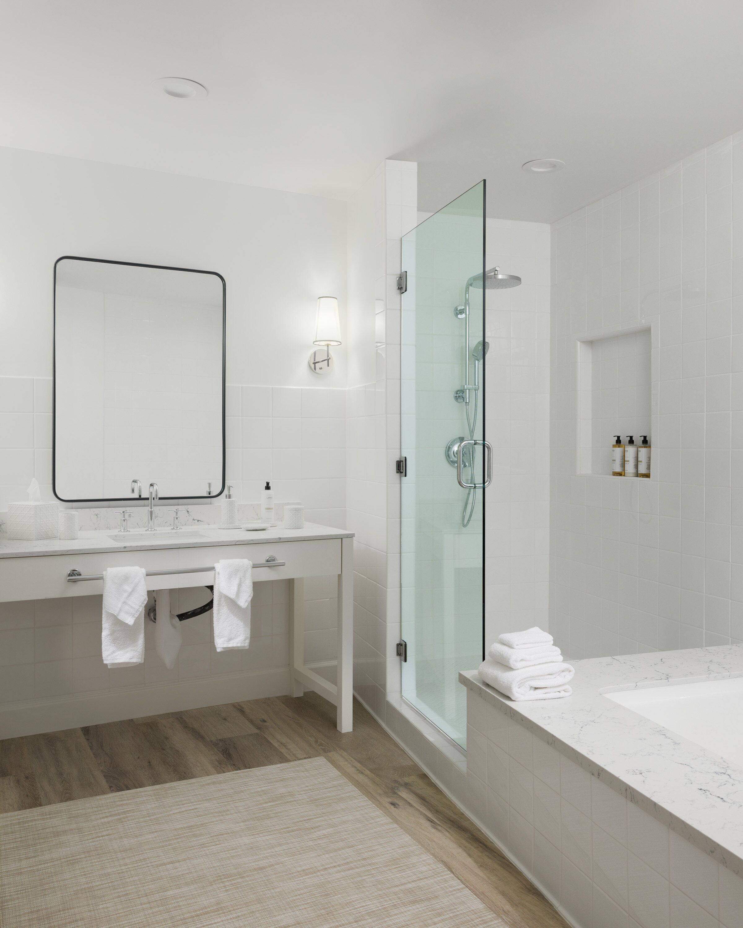 A modern bathroom with a glass-enclosed shower, a large mirror, and a vanity with a sink and towel rack.