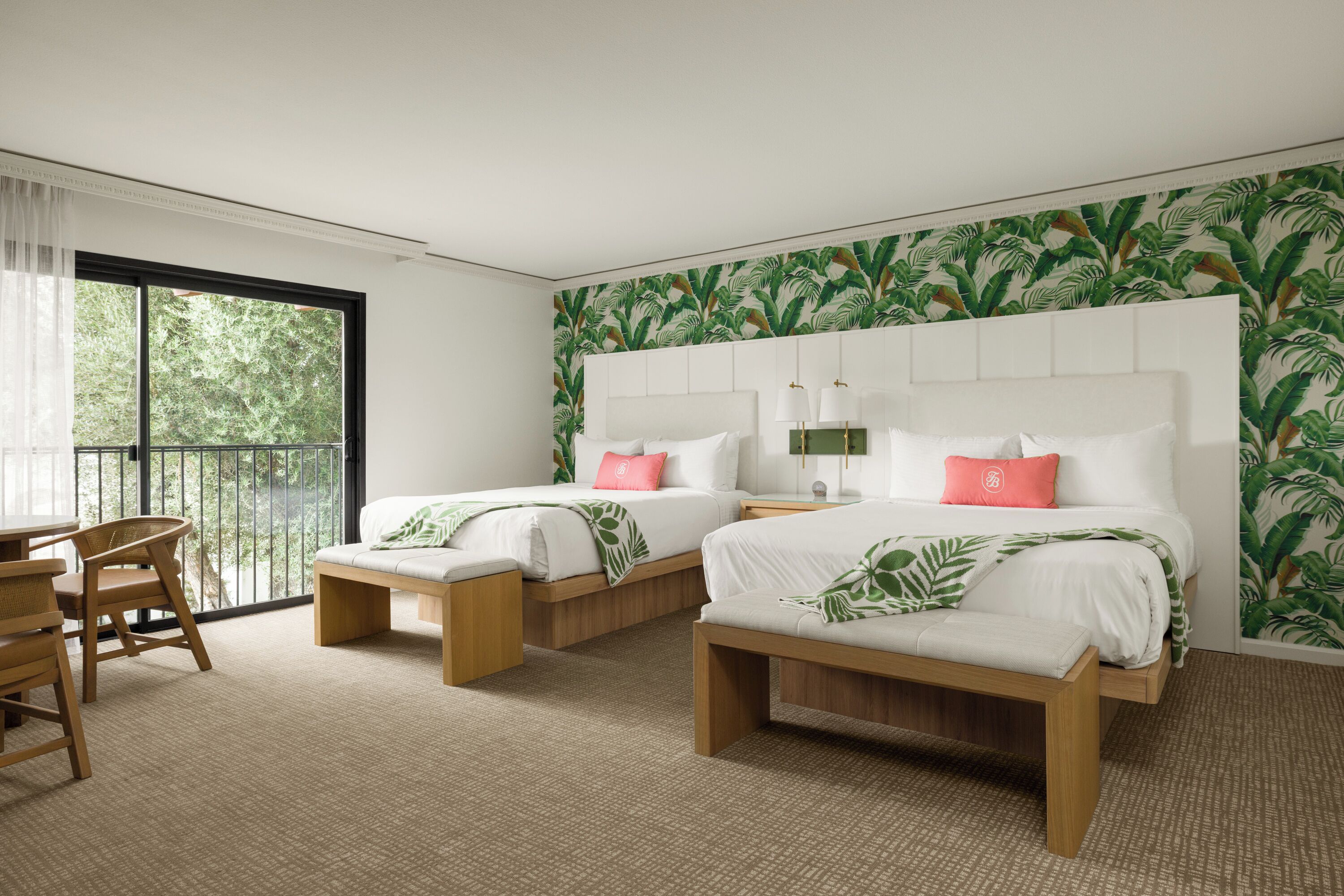 Une chambre d’hôtel avec deux lits, un balcon et une vue sur les arbres.