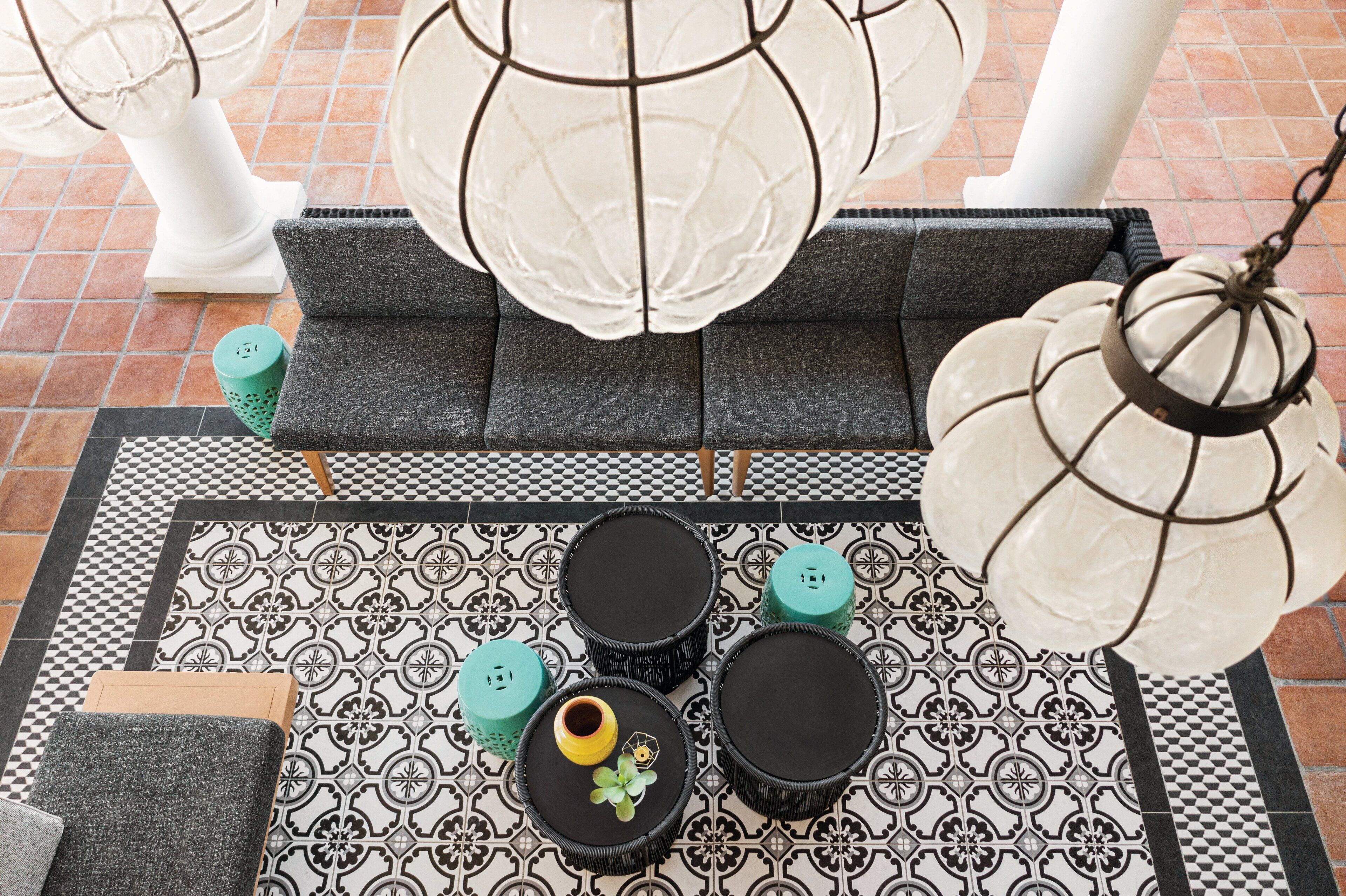 A tiled patio area with a patterned floor, a grey sofa, and a hanging light fixture.
