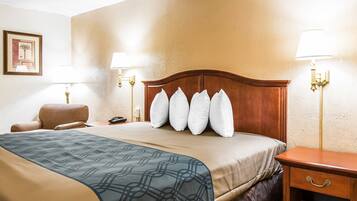 A hotel room with a large bed, a wooden nightstand, a chair, and two wall-mounted lamps.