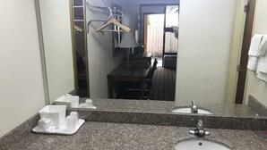 A bathroom with granite countertops, two sinks, a mirror, and a towel rack. - Econo Lodge Savannah Midtown (Savannah)