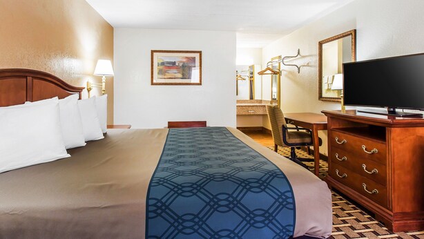 A hotel room with a bed, a desk, a dresser, a television, and a painting on the wall. - Econo Lodge Savannah Midtown (Savannah)