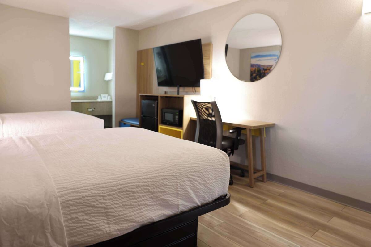 Une chambre d’hôtel comprenant un lit, un bureau, une chaise, une télévision et un miroir.