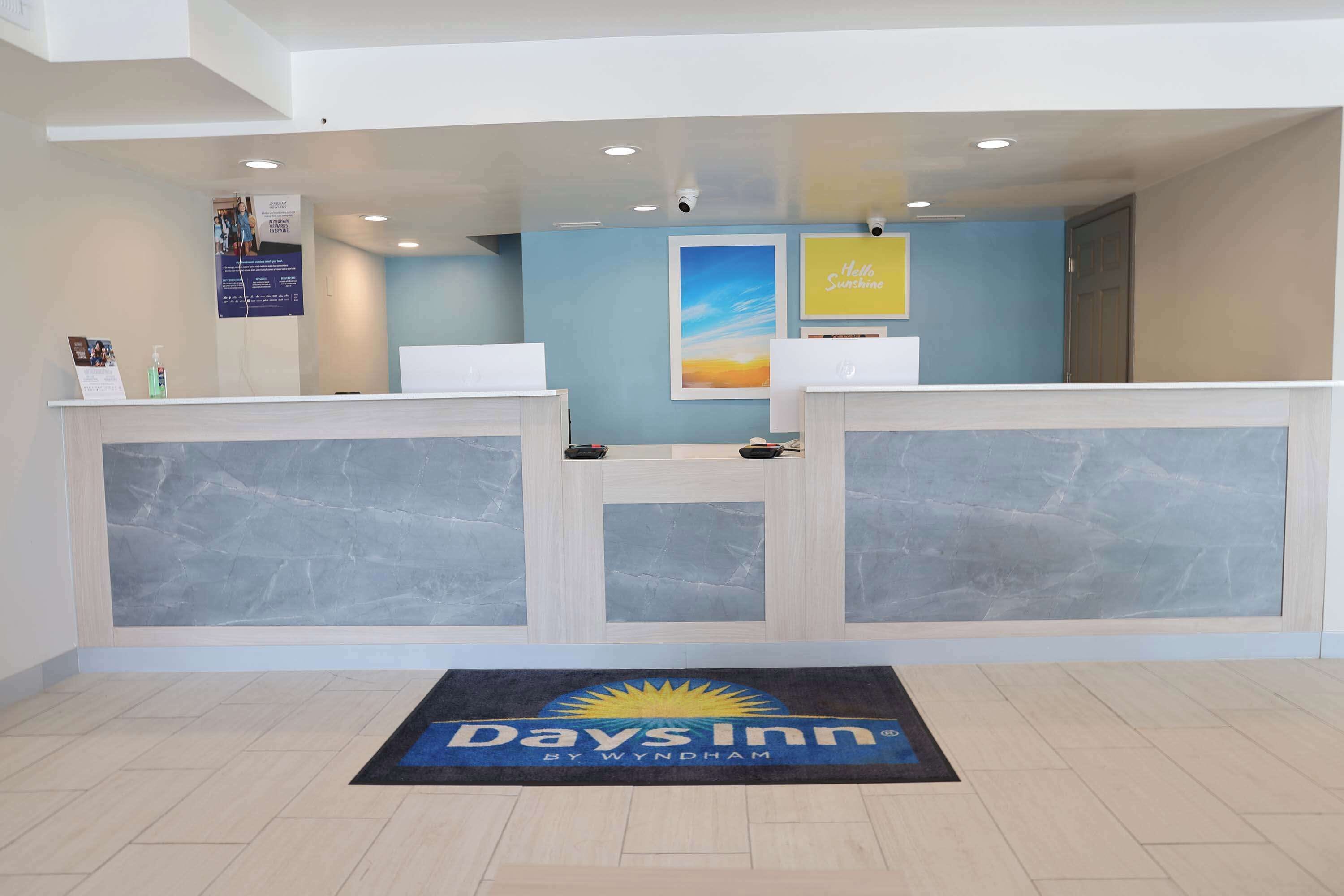 Un área de recepción con mostradores de mármol, una pared azul y un tapete de 'Days Inn by Wyndham'.