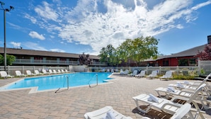 Une piscine avec des chaises longues et une terrasse en briques.