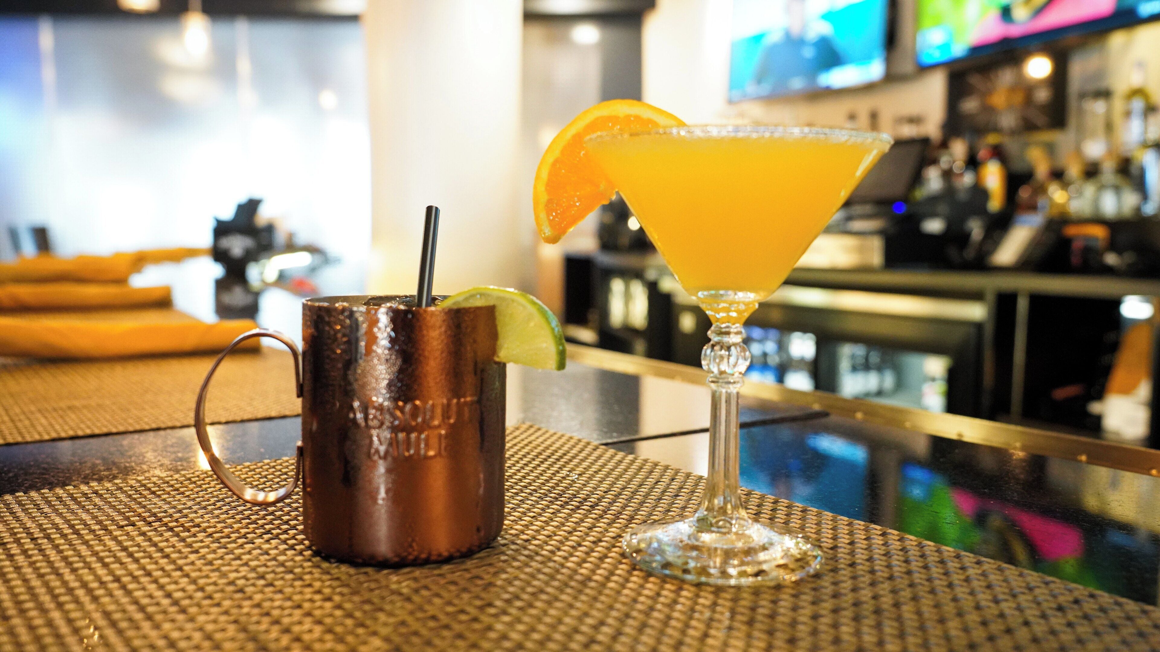 A bar area with a copper mug and a martini glass on a woven mat.