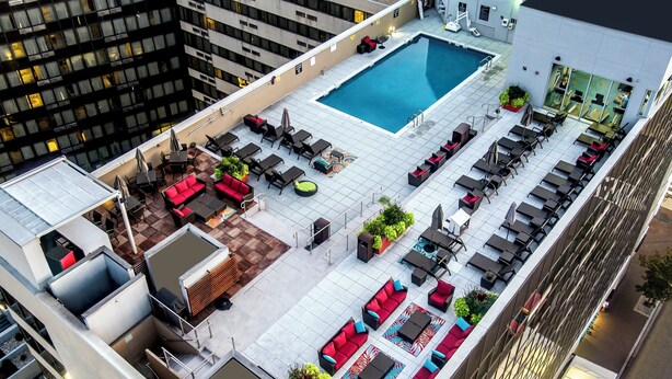 A rooftop pool area with multiple seating arrangements, a swimming pool, and a view of surrounding buildings. - Holiday Inn Washington Capitol - Natl Mall by IHG (Washington)